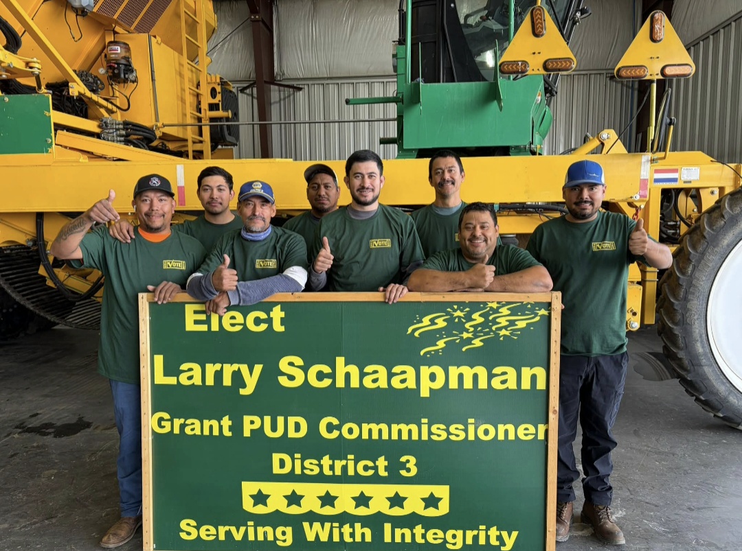 Farm crew giving thumbs up behind an Elect Larry Schaapman sign